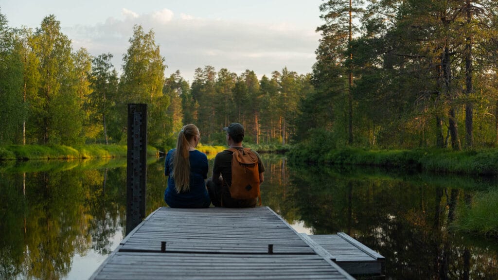 Visit Rautavaara. Kaksi henkilöä istuu Rautavaaralla laiturin päässä.